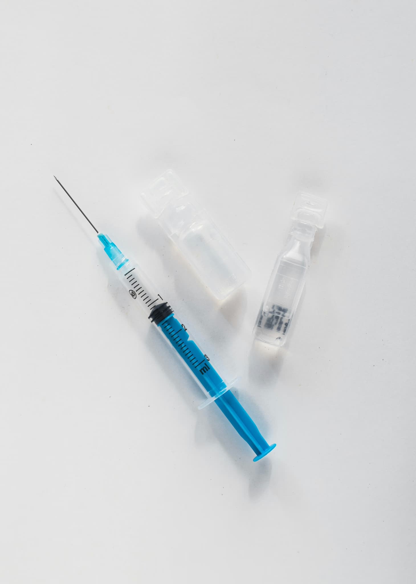 Syringe and vaccine vials on a white surface